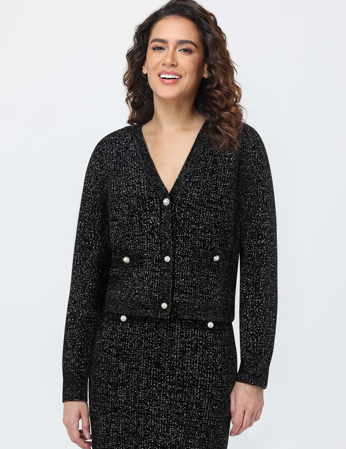 Woman wearing a black textured suit with white buttons on a light gray background