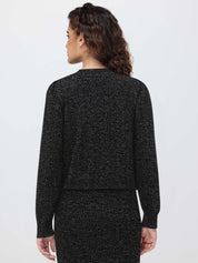 Person wearing a black textured cardigan and skirt set on a light gray background