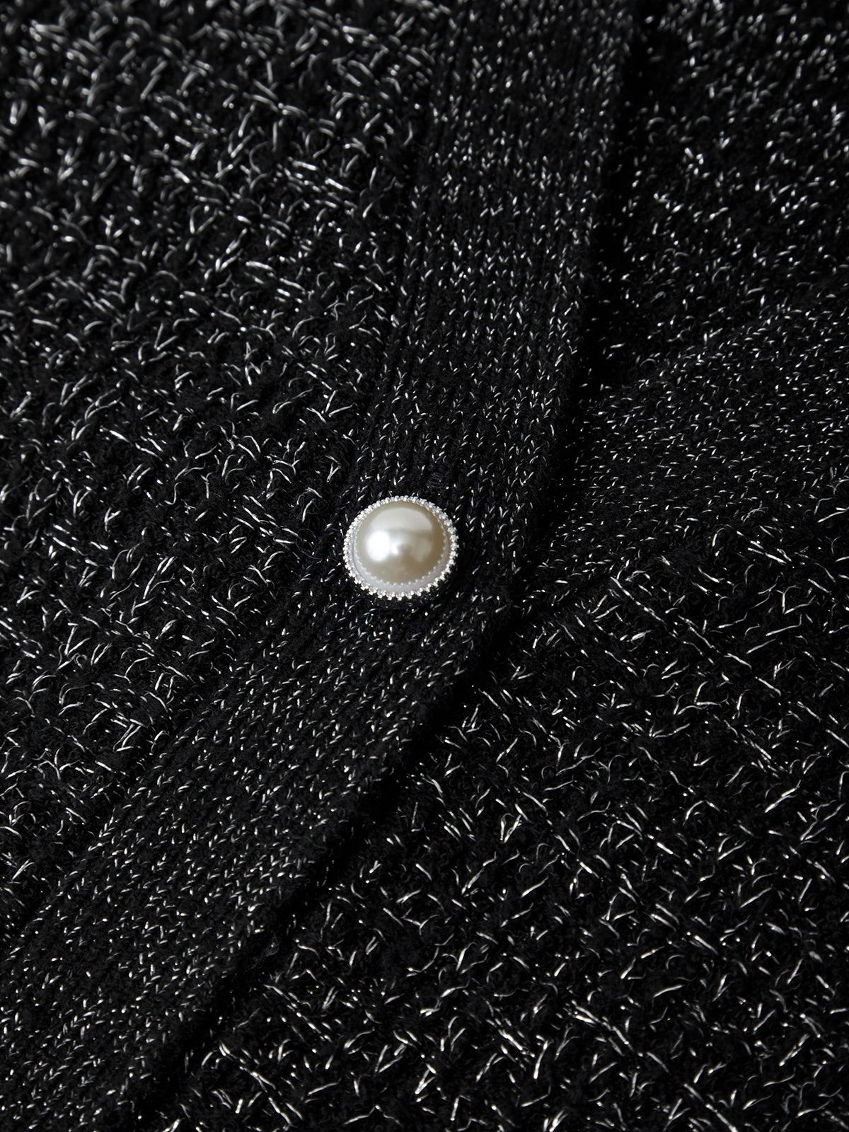 Close-up of a black textured fabric with a pearl button.