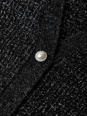 Close-up of a black textured fabric with a pearl button.