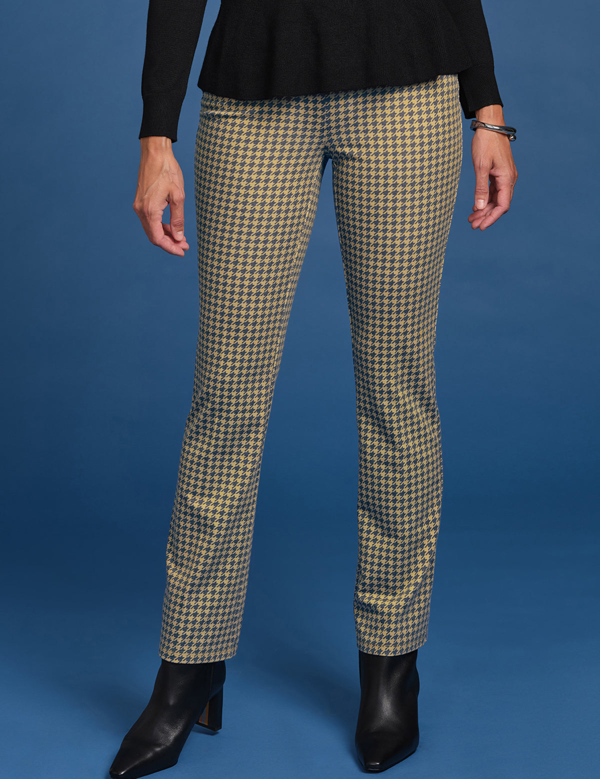 Person wearing houndstooth patterned pants on a blue background