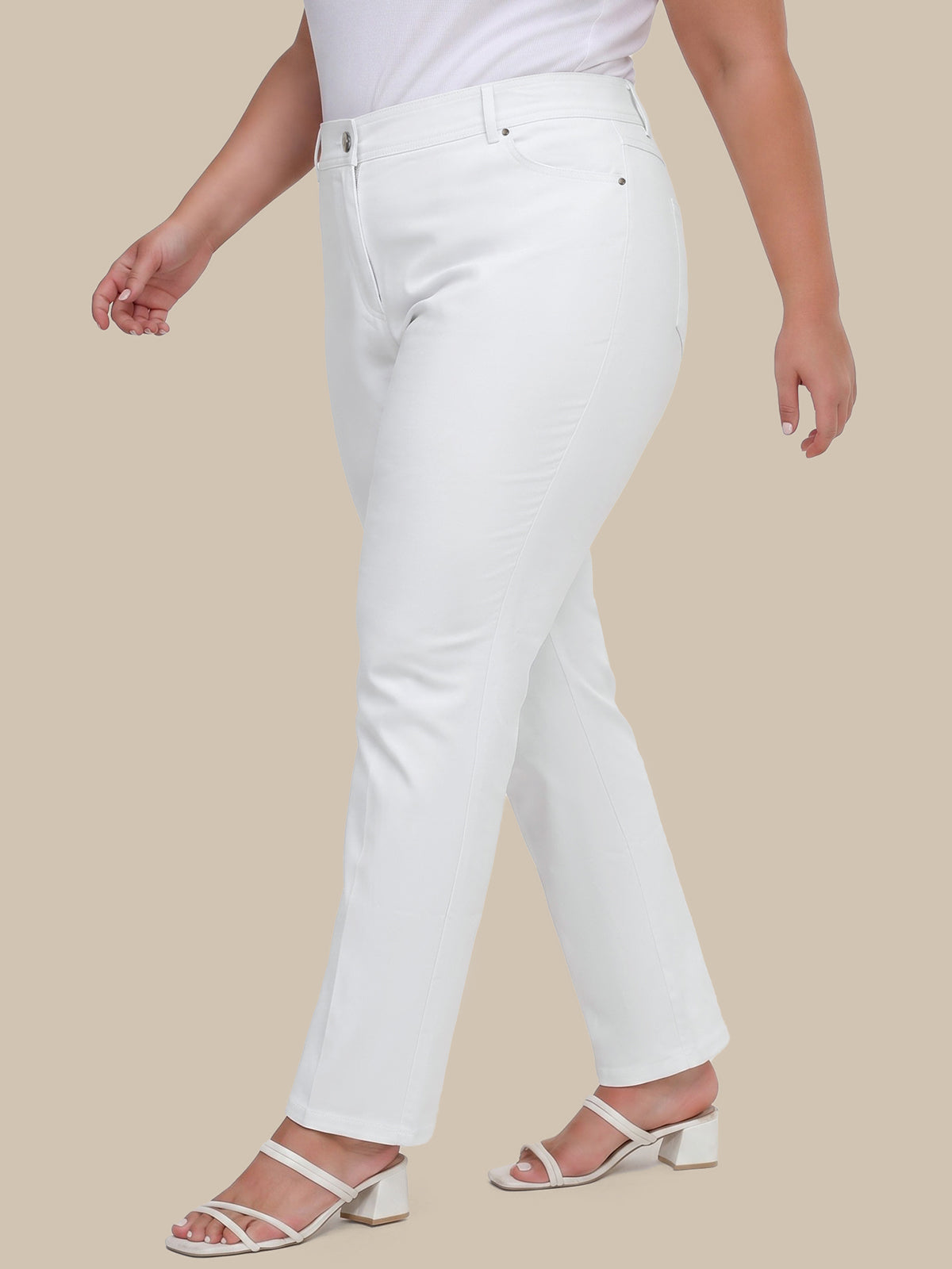 Person wearing white jeans on a beige background