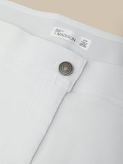 Close-up of a white pants pocket with a button and '89th Madison' label on a beige background