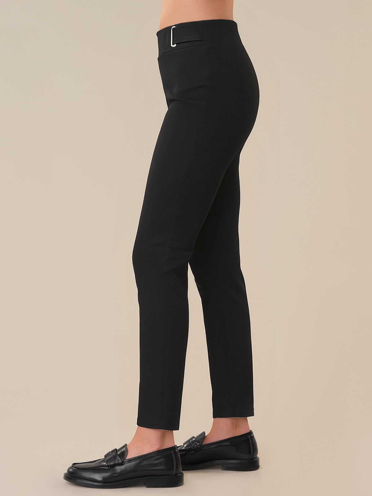 Black pants worn by a person on a beige background