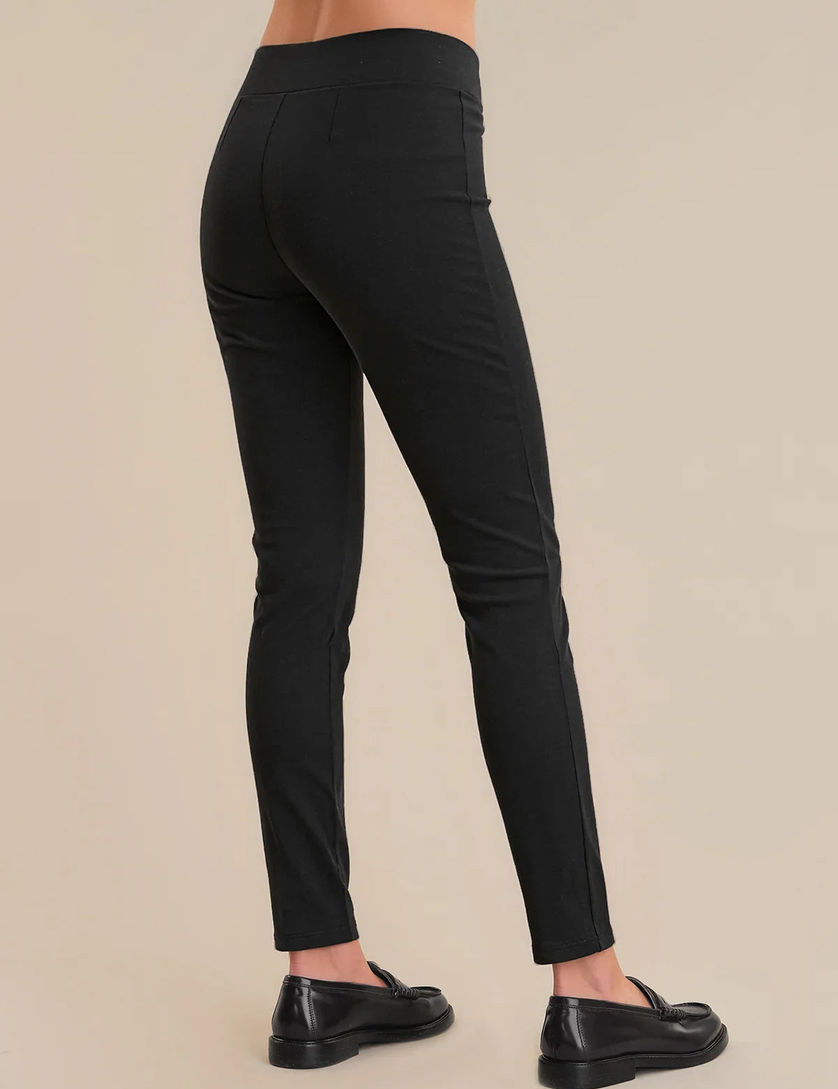 Black pants worn by a person on a beige background