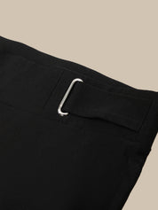 Close-up of black pants with a metal buckle on a beige background