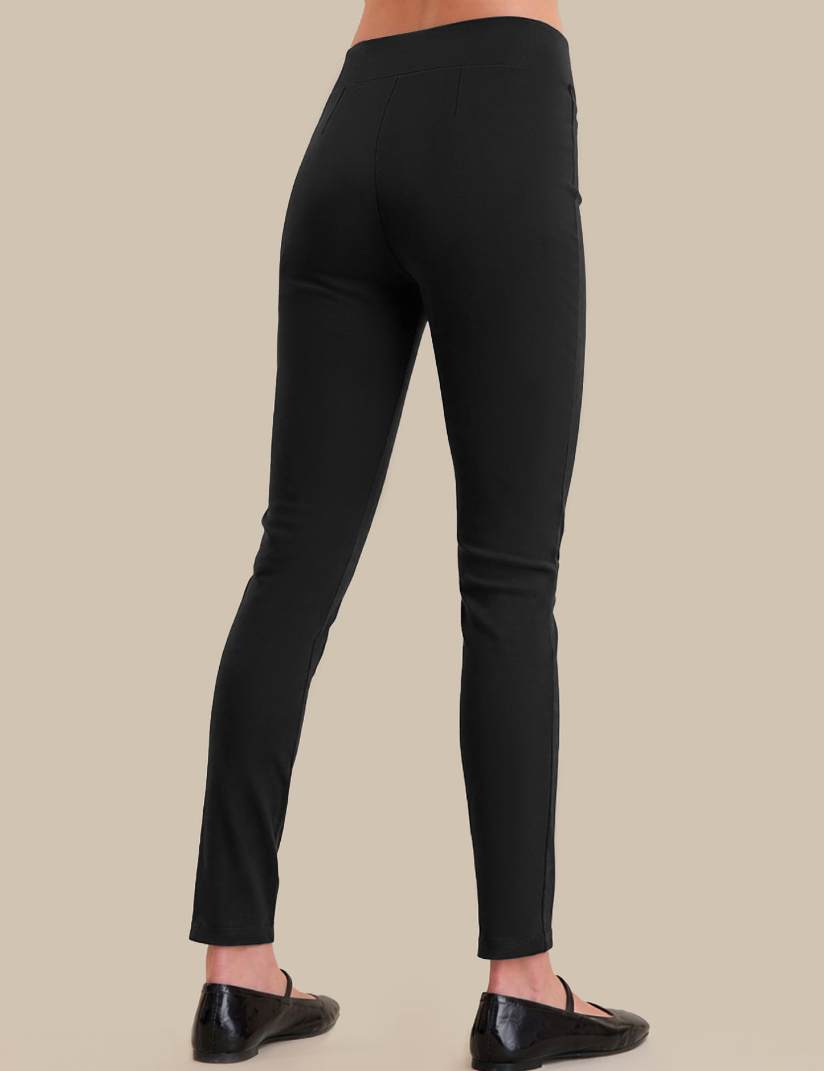 Black leggings worn by a person on a beige background