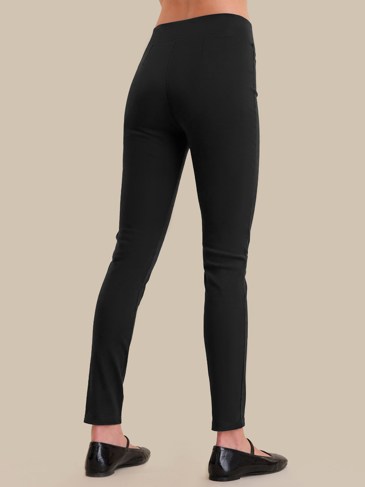 Black leggings worn by a person on a beige background