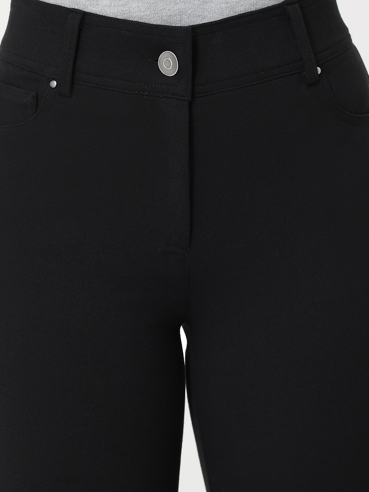 Close-up of black pants with a button on a white background
