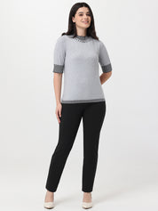 Woman wearing a gray sweater with black trim and black pants on a white background
