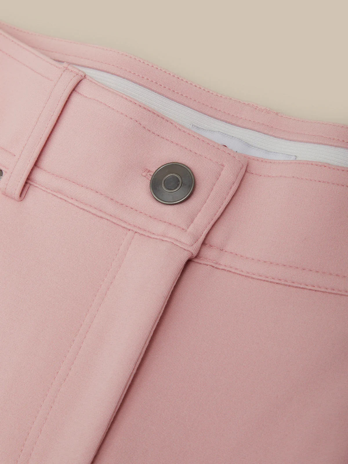 Close-up of pink pants with a button on a beige background