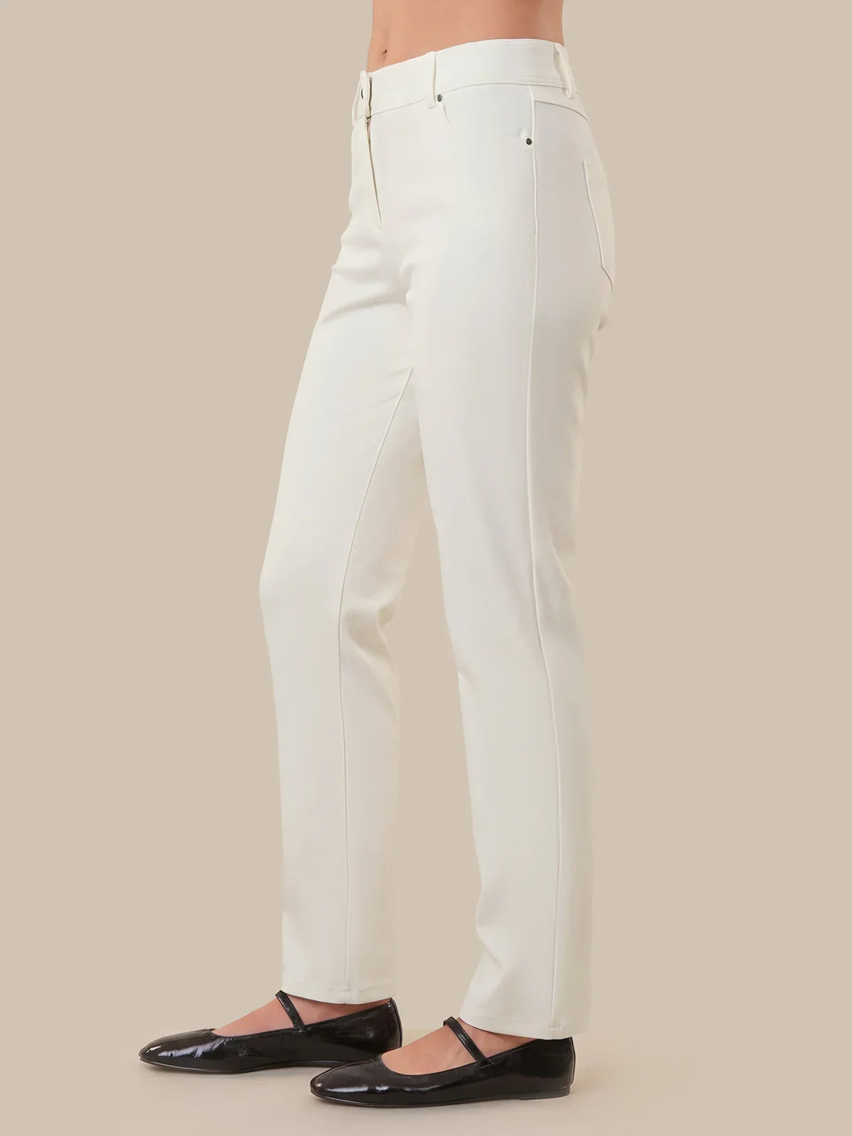 White pants worn by a person on a beige background