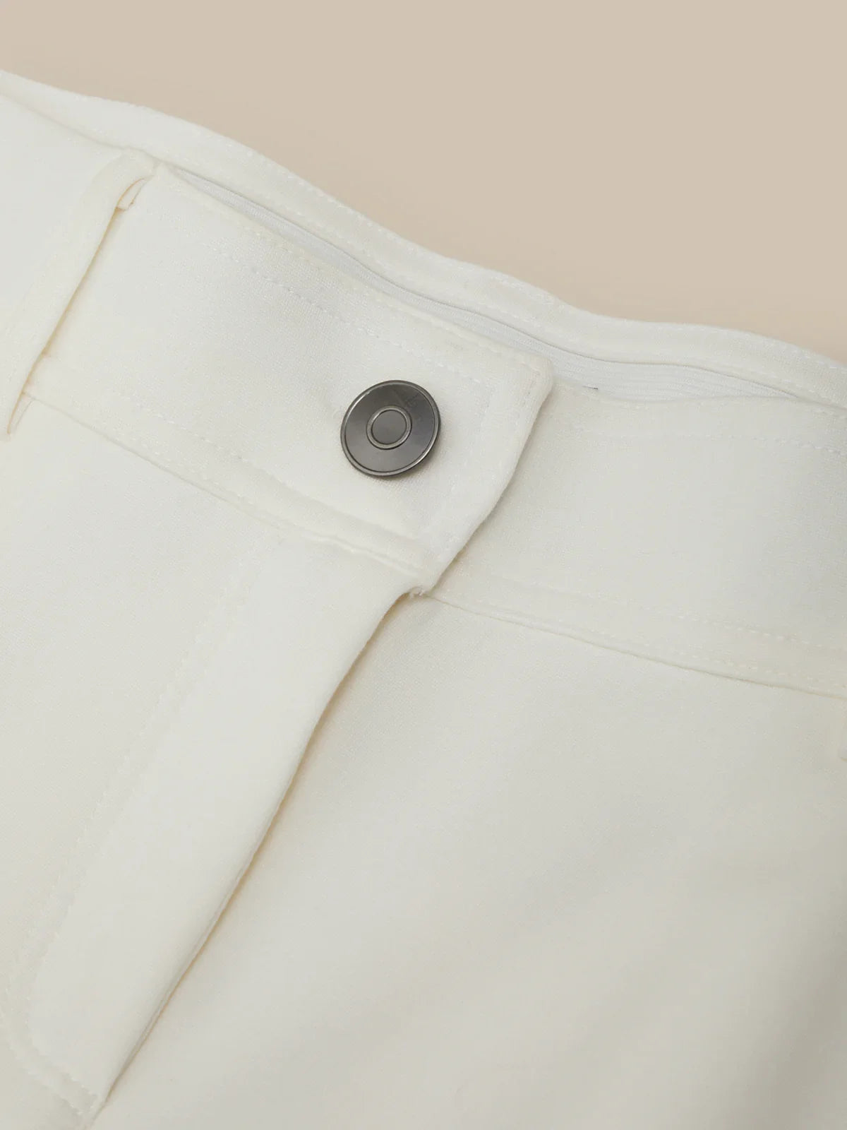 Close-up of a button on a white garment against a beige background