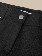 Close-up of dark charcoal gray textured trousers showing the waistband, button closure, and fabric weave against a beige background.