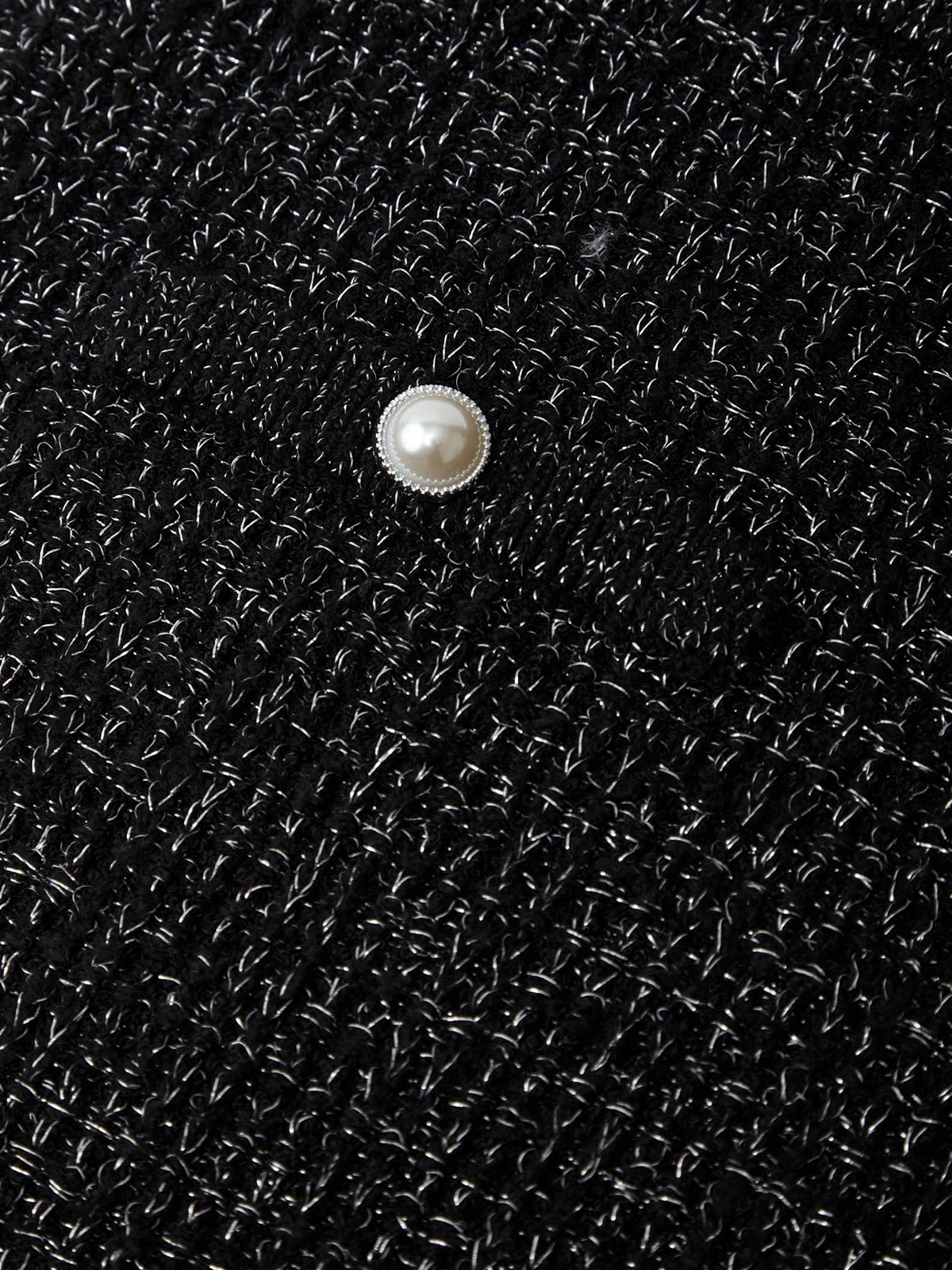 Pearl button on a black textured fabric background
