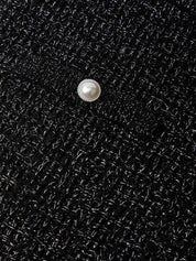 Pearl button on a black textured fabric background