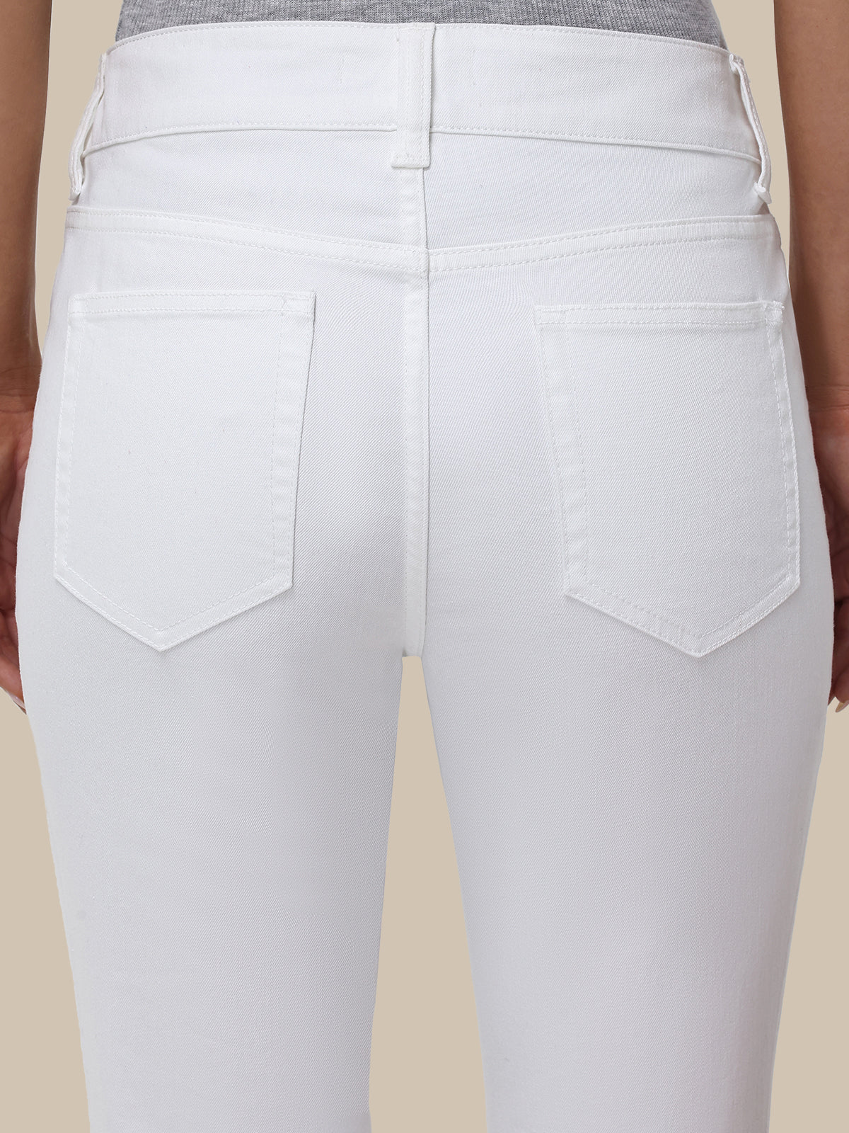 White jeans worn by a person on a beige background