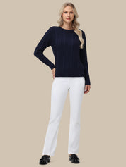 Woman wearing a navy sweater and white pants on a beige background