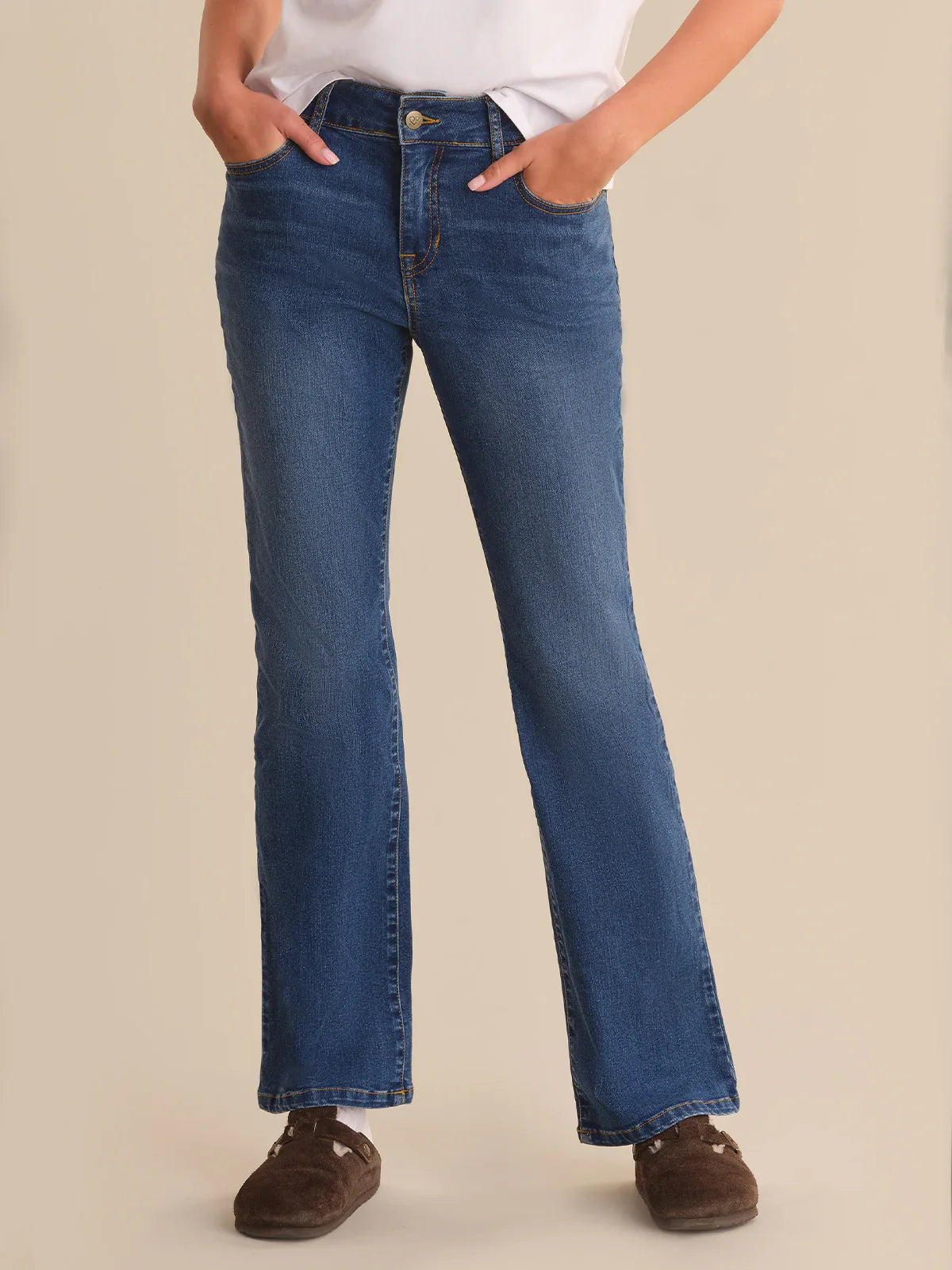 Person wearing blue jeans on a beige background