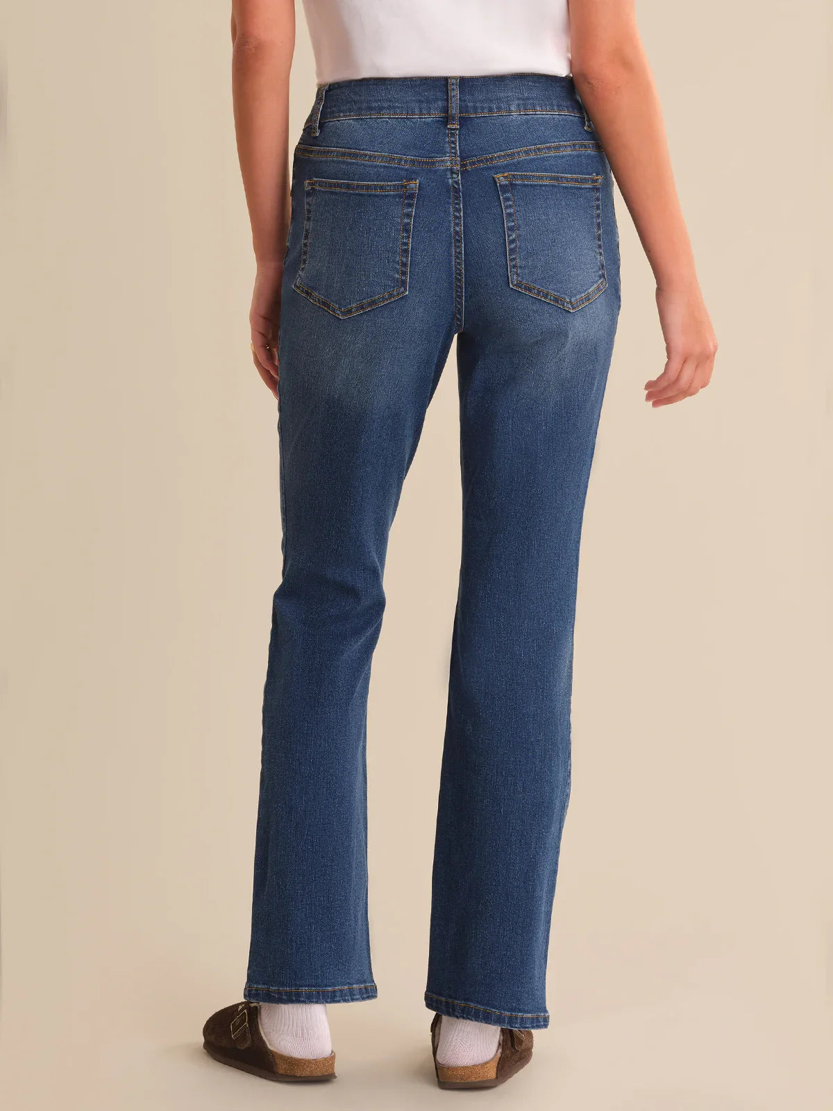 Person wearing blue jeans on a beige background
