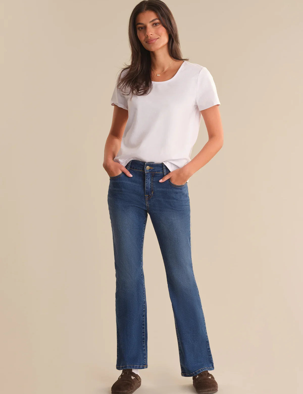 Woman wearing a white t-shirt and blue jeans on a beige background