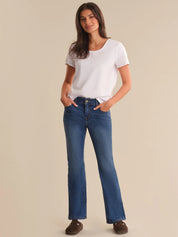 Woman wearing a white t-shirt and blue jeans on a beige background