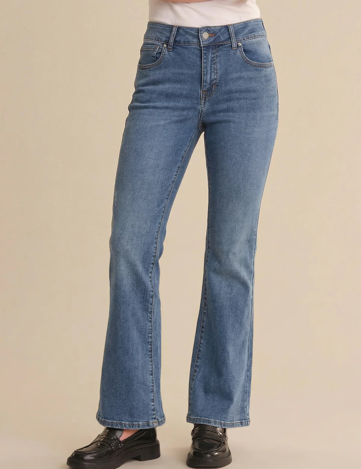 Blue jeans worn by a person on a beige background