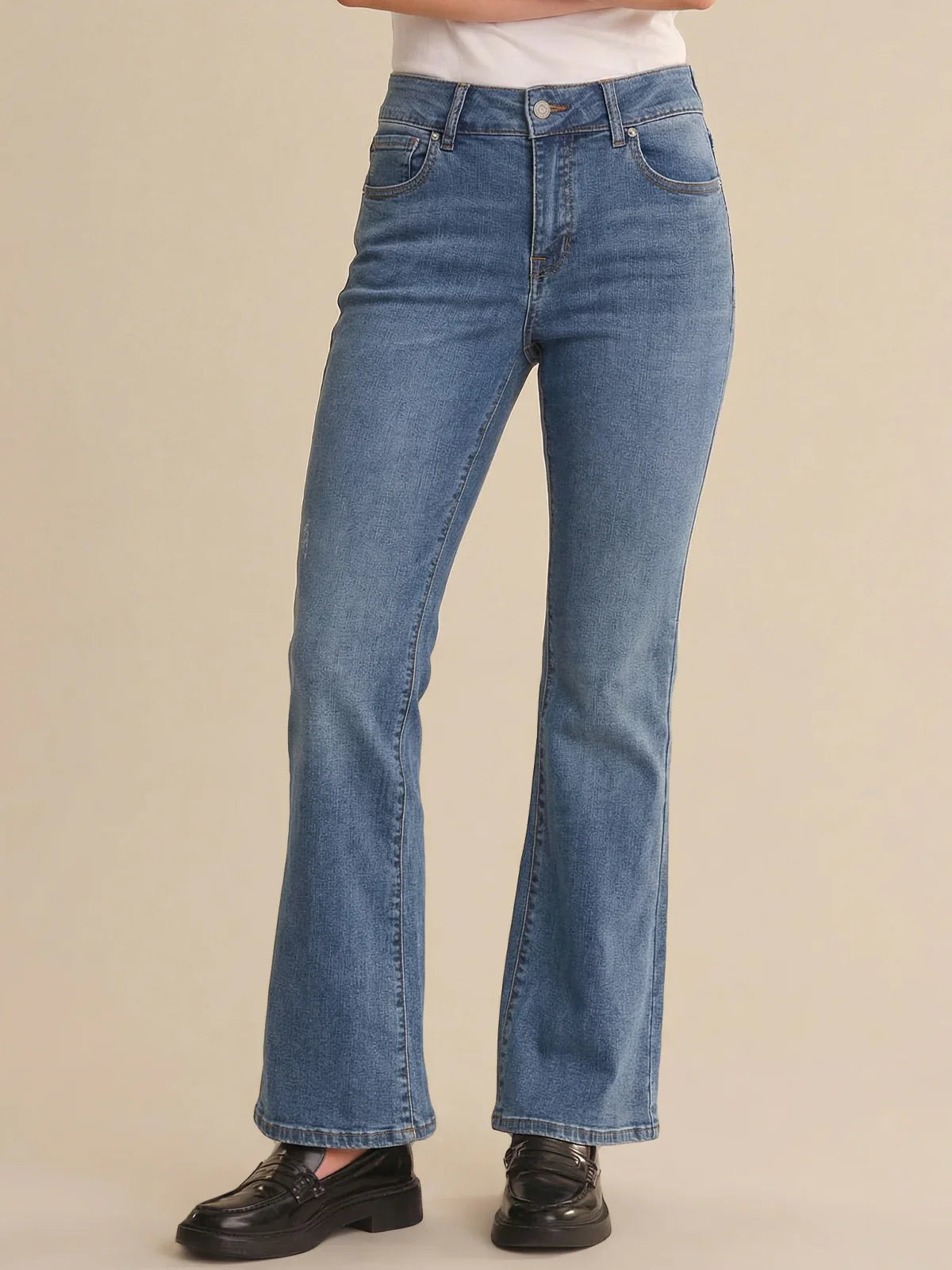 Blue jeans worn by a person on a beige background