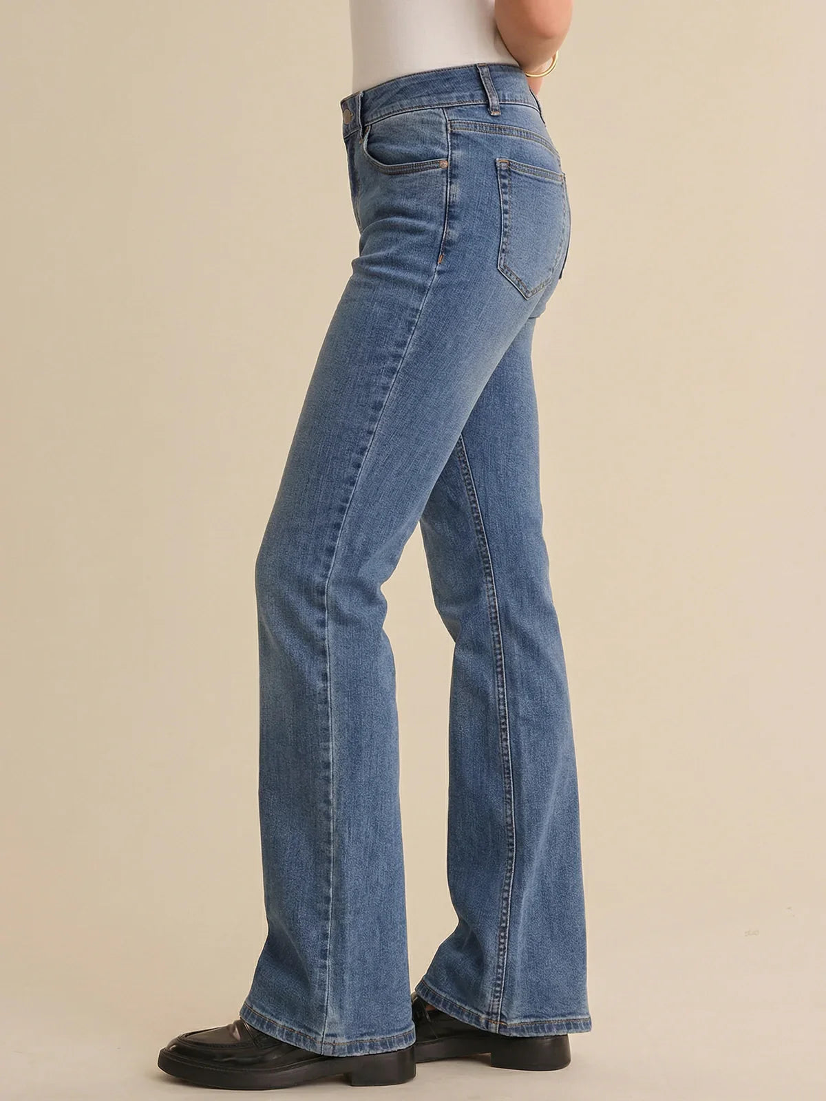 Blue jeans worn by a person on a beige background