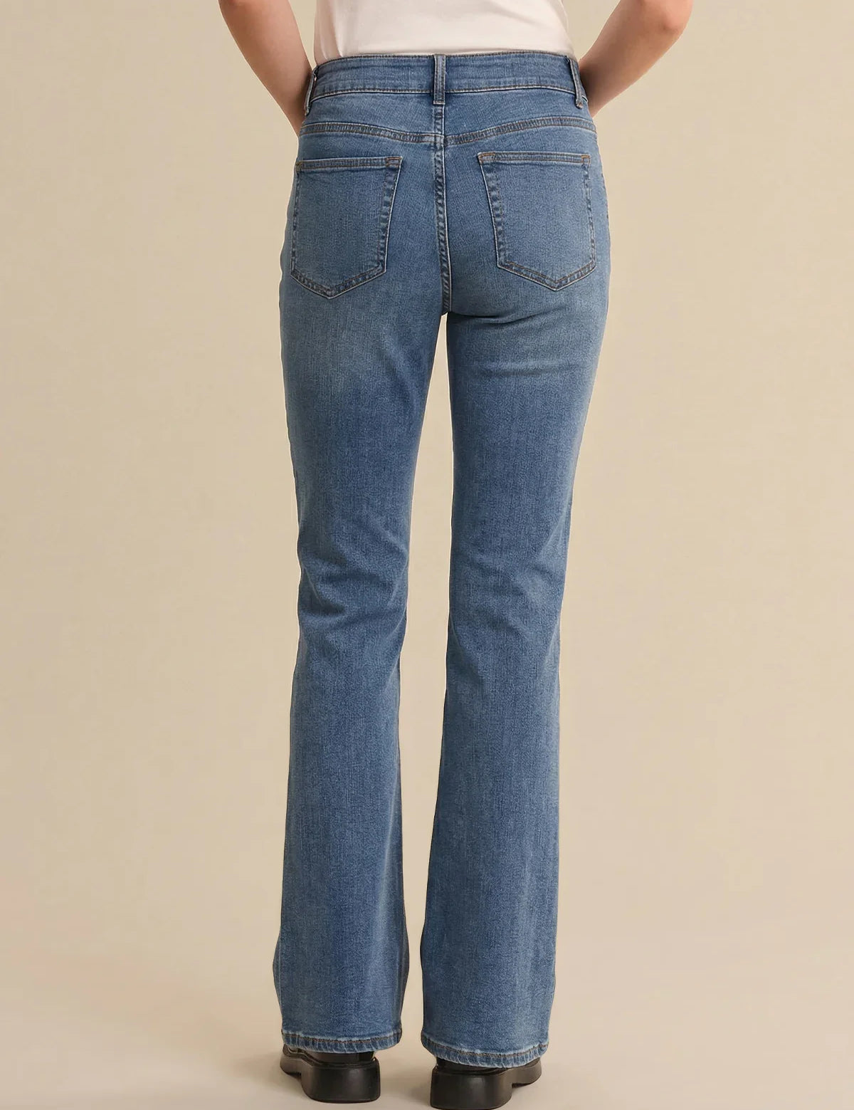 Person wearing blue jeans on a beige background