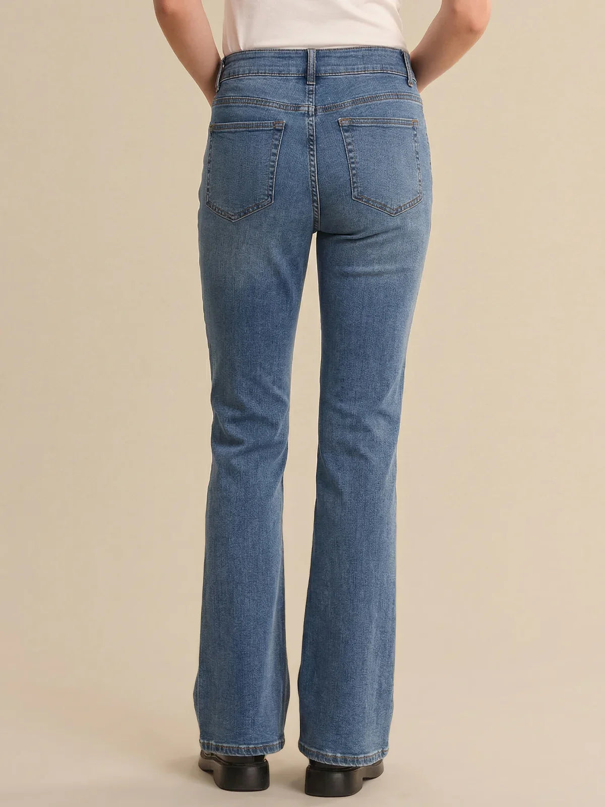 Person wearing blue jeans on a beige background