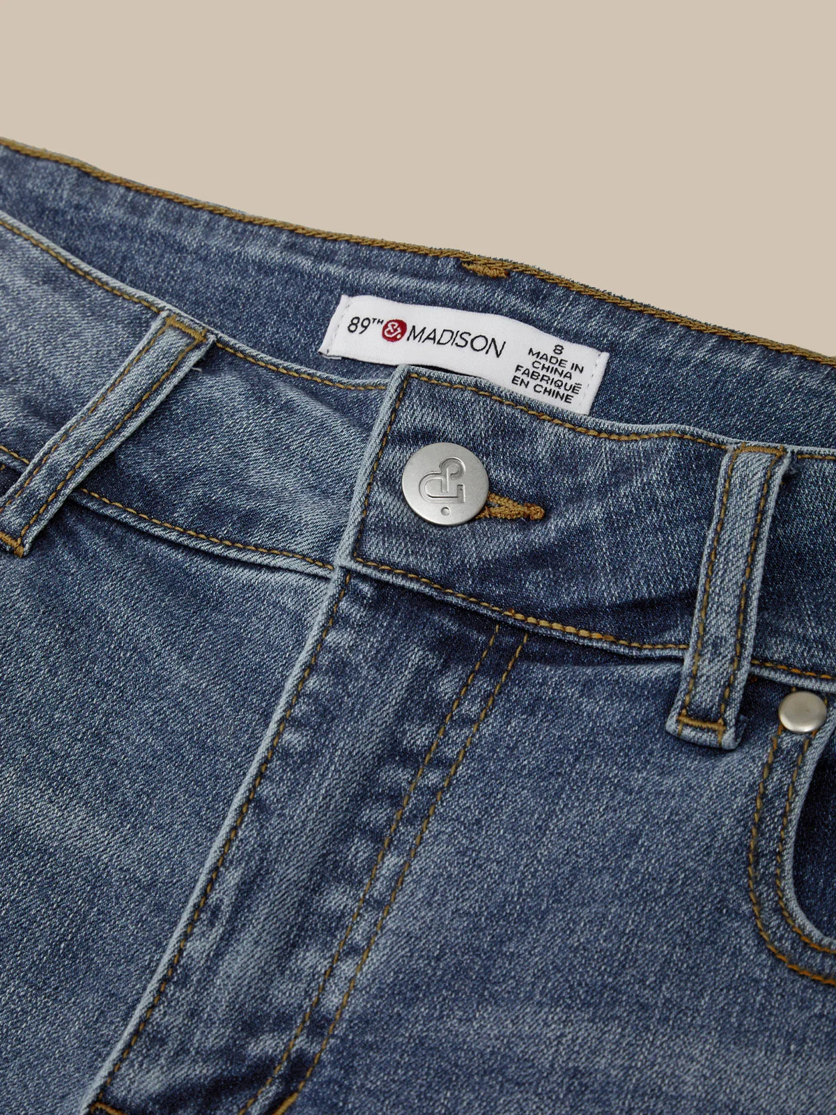 Close-up of blue denim jeans with a brand label on a beige background