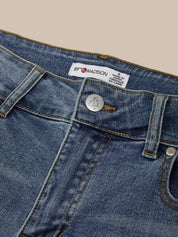 Close-up of blue denim jeans with a brand label on a beige background
