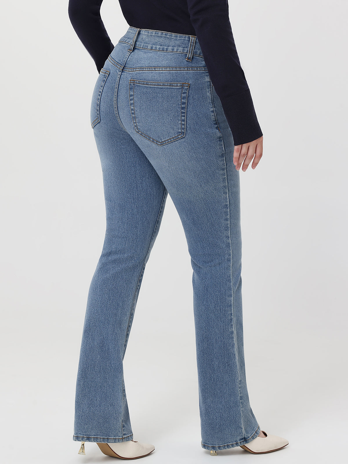 Person wearing blue flared jeans and a black top on a white background