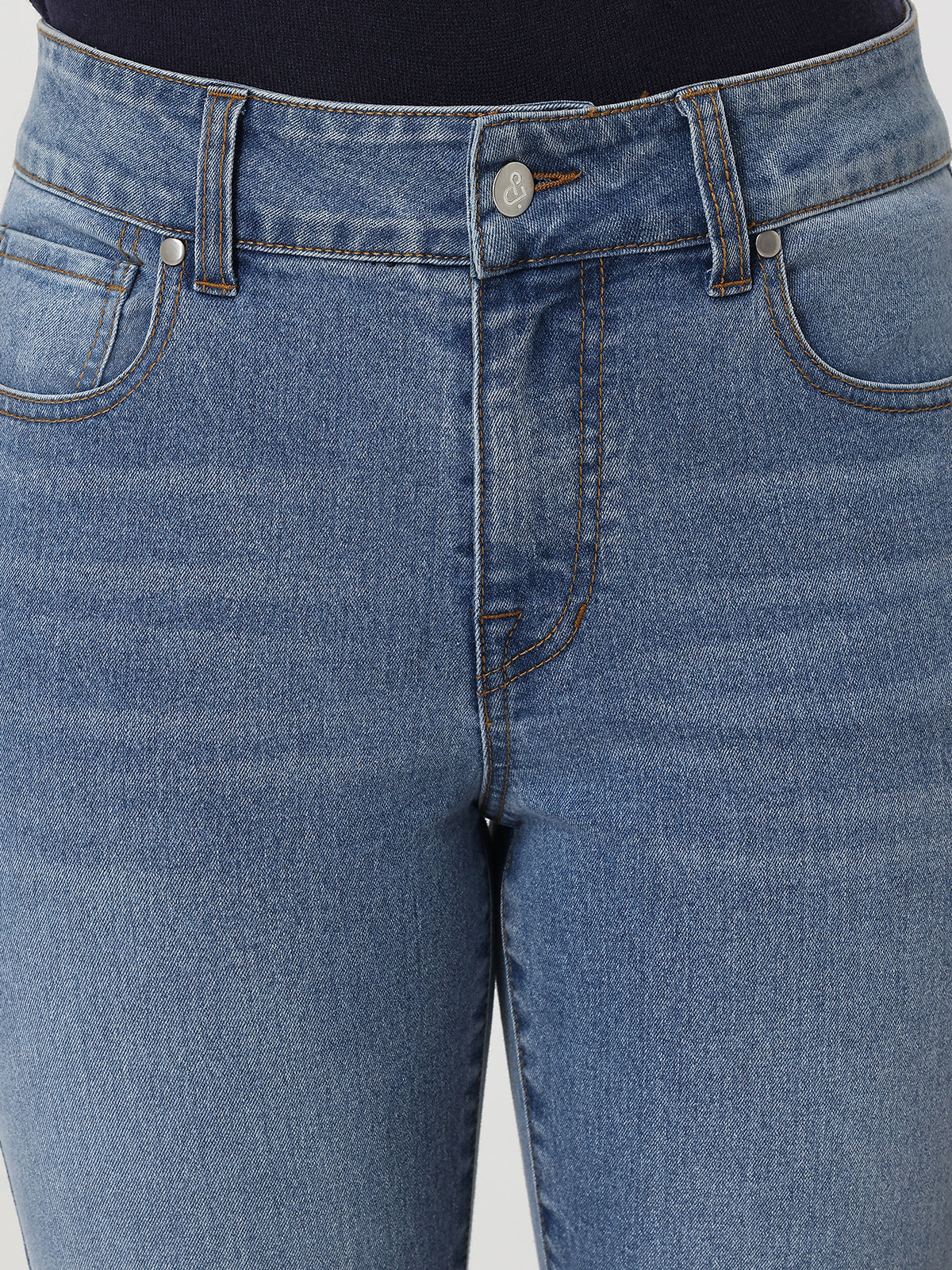 Close-up of blue jeans with a focus on the waistband and front pocket.