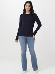Woman wearing a navy sweater and light blue jeans on a white background