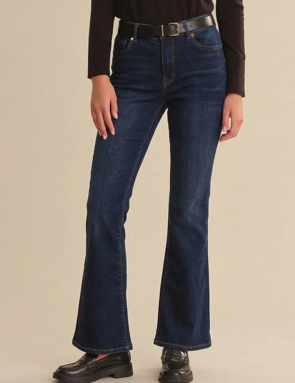 Person wearing blue jeans on a beige background