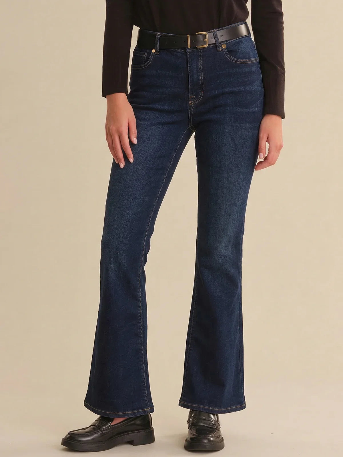 Person wearing blue jeans on a beige background
