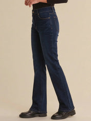 Person wearing dark blue jeans on a beige background
