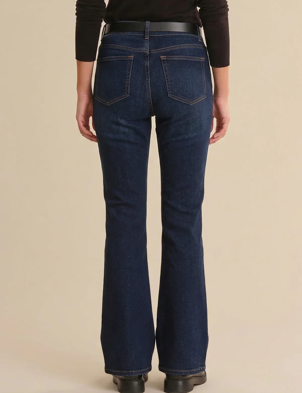 Person wearing blue jeans on a beige background