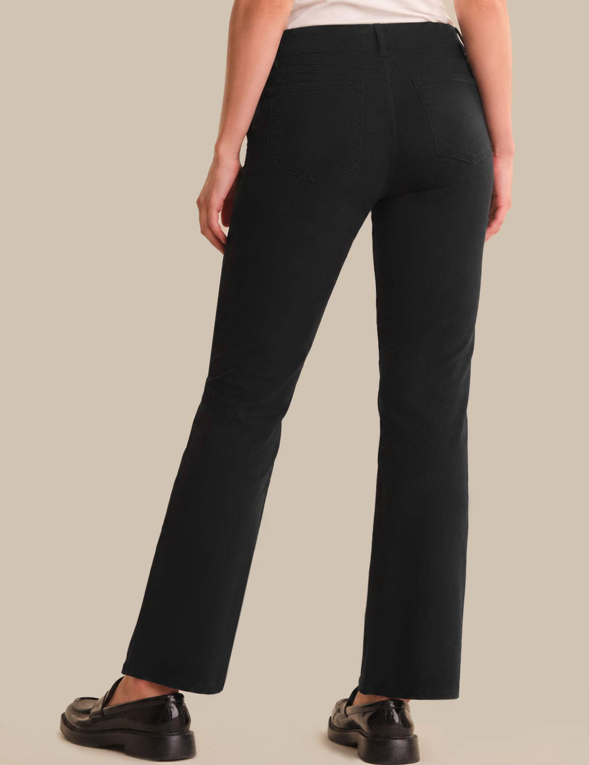 Person wearing black pants on a beige background