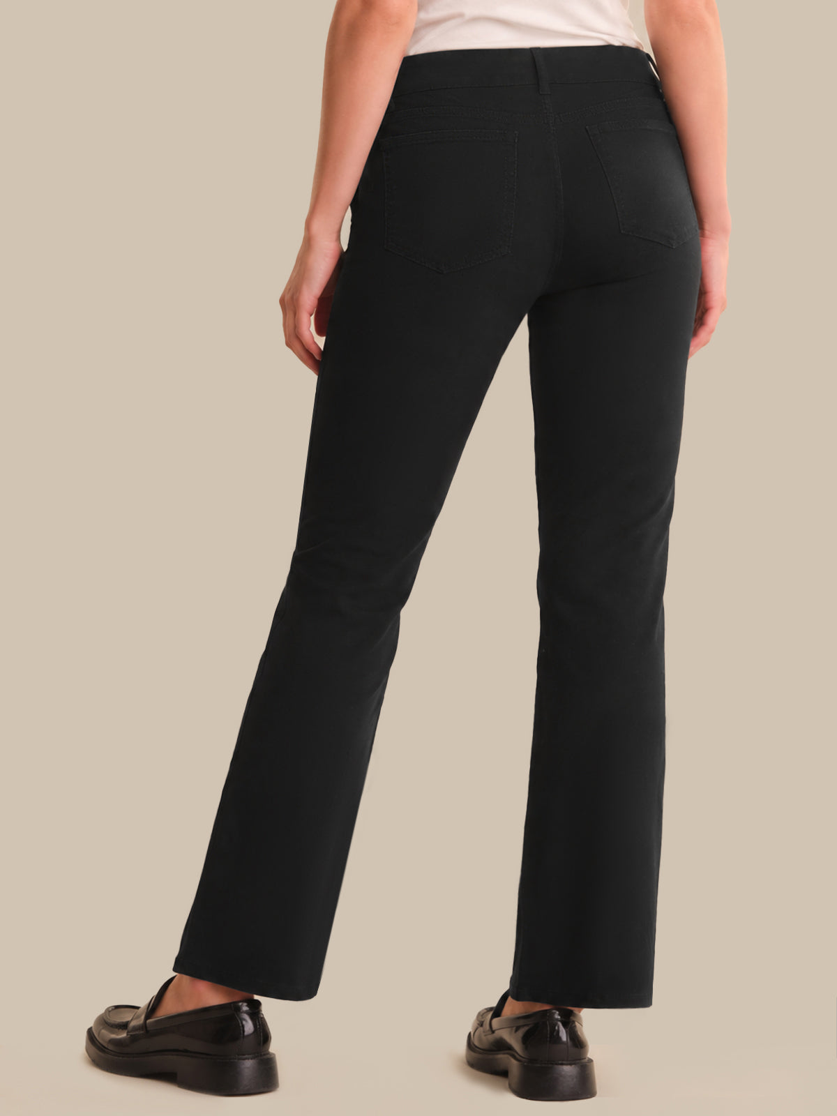 Person wearing black pants on a beige background