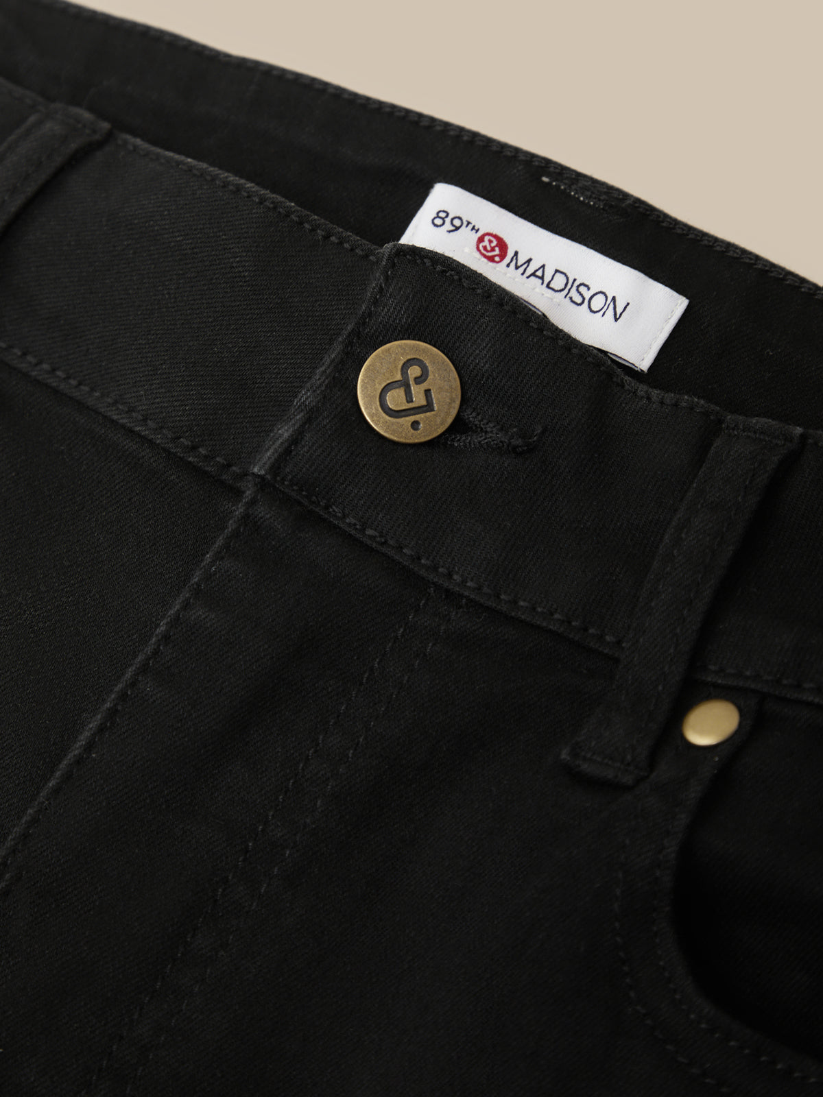 Close-up of black pants with a brand label and button details.