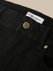 Close-up of black pants with a brand label and button details.