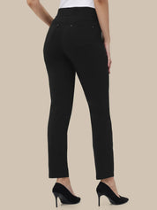 Black slim-fit ankle-length pants shown on a model from the back, paired with a white top and black high heels, against a solid beige background.