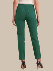 A model shown from the back wearing a pair of slim-fit green trousers with a high waistband, back pockets, and a straight leg, paired with black high heels against a solid beige background.