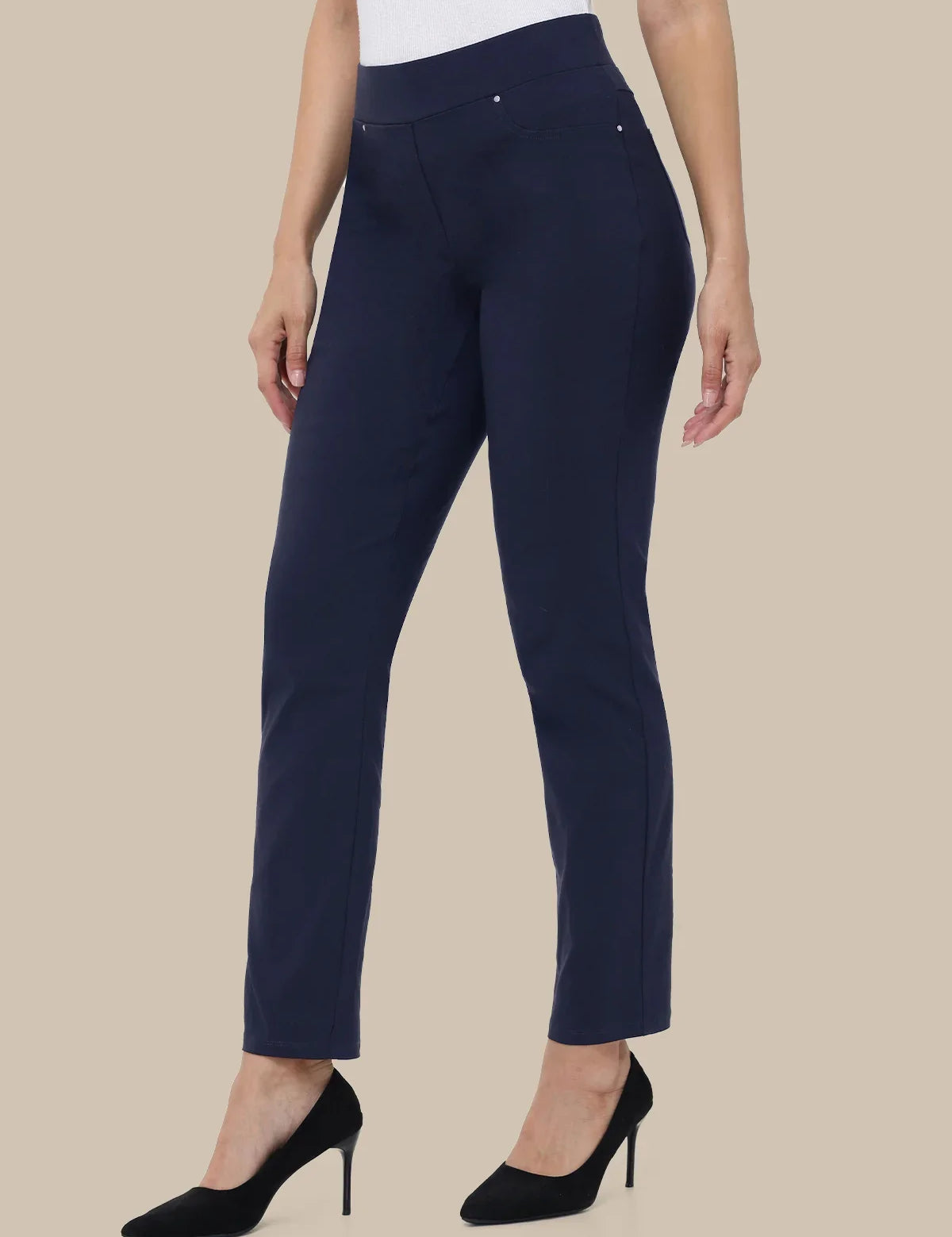 A model wearing navy blue cropped trousers with a white top and black high heels, shown from the waist down against a solid beige background.