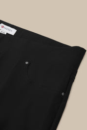 Close-up of black pants with a Mansur Gavriel label on a beige background