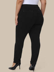 A model shown from the back wearing black high-waisted slim-fit pants with a white top and black heels, set against a solid beige background.