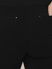 Close-up of the back of black pants showing two back pockets with silver rivets and a hand in the right pocket.